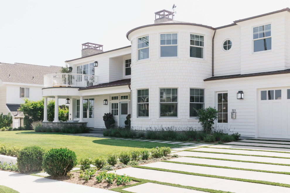 Foto della villa grande bianca stile marinaro a due piani con rivestimento in legno, tetto a capanna e copertura in metallo o lamiera