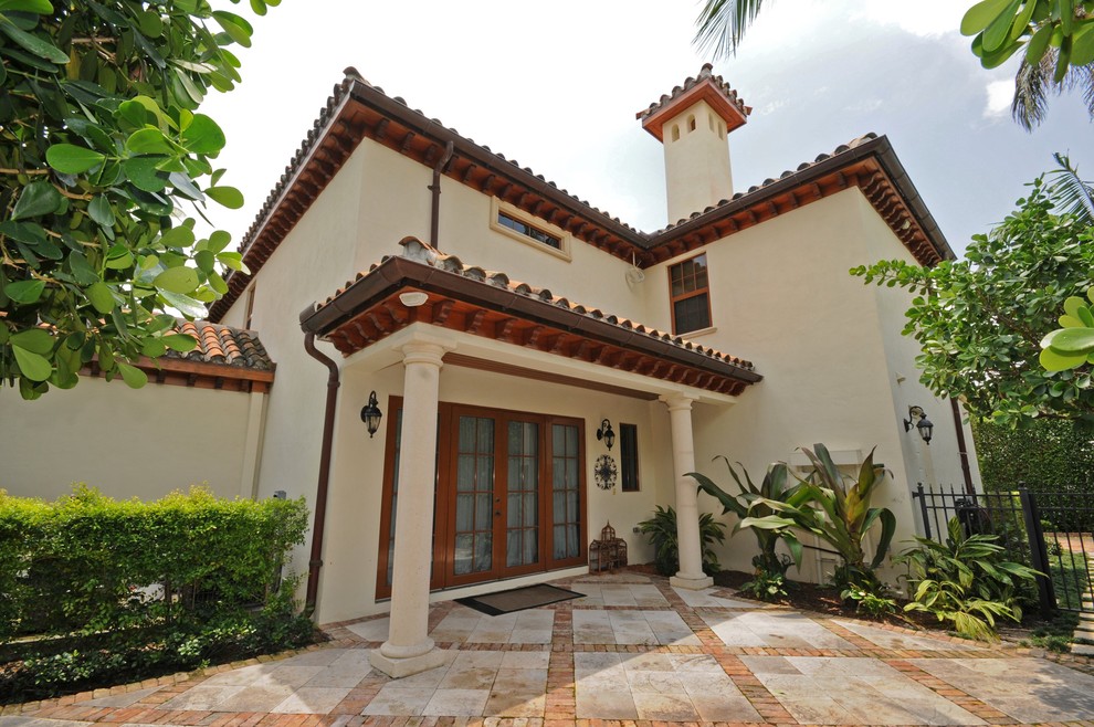 Стильный дизайн: большой, двухэтажный, бежевый частный загородный дом в средиземноморском стиле с облицовкой из цементной штукатурки, вальмовой крышей и черепичной крышей - последний тренд
