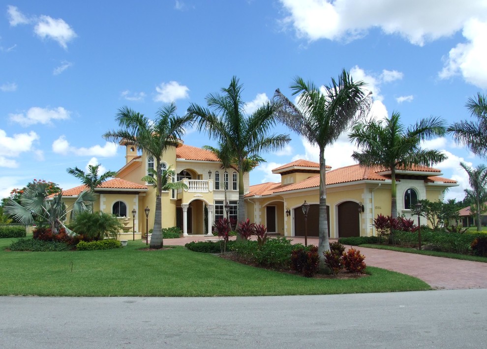 Zweistöckiges Mediterranes Haus mit gelber Fassadenfarbe und Walmdach in Miami