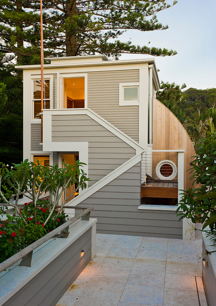 На фото: двухэтажный, бежевый дом среднего размера в морском стиле с плоской крышей