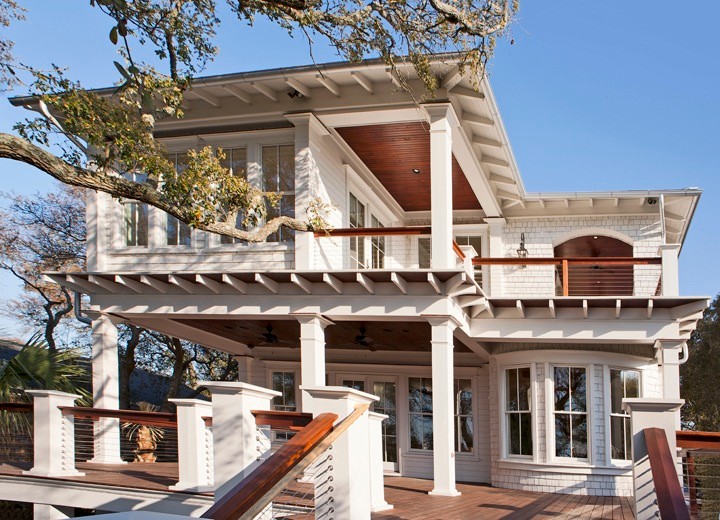 Ejemplo de fachada blanca tropical grande de dos plantas con revestimiento de madera y tejado a cuatro aguas