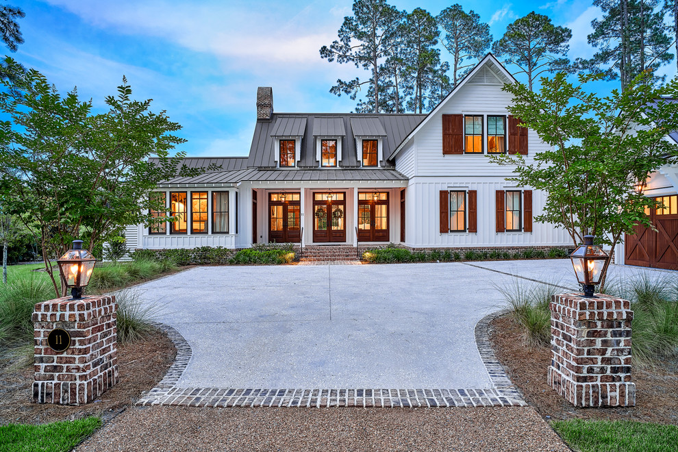 Foto della facciata di una casa grande bianca country a due piani con rivestimento con lastre in cemento, tetto a capanna, copertura in metallo o lamiera e tetto grigio