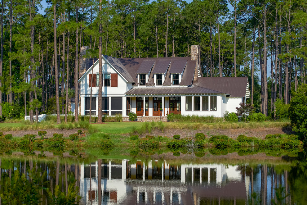 Foto della facciata di una casa grande bianca country a due piani con rivestimento con lastre in cemento e tetto a capanna