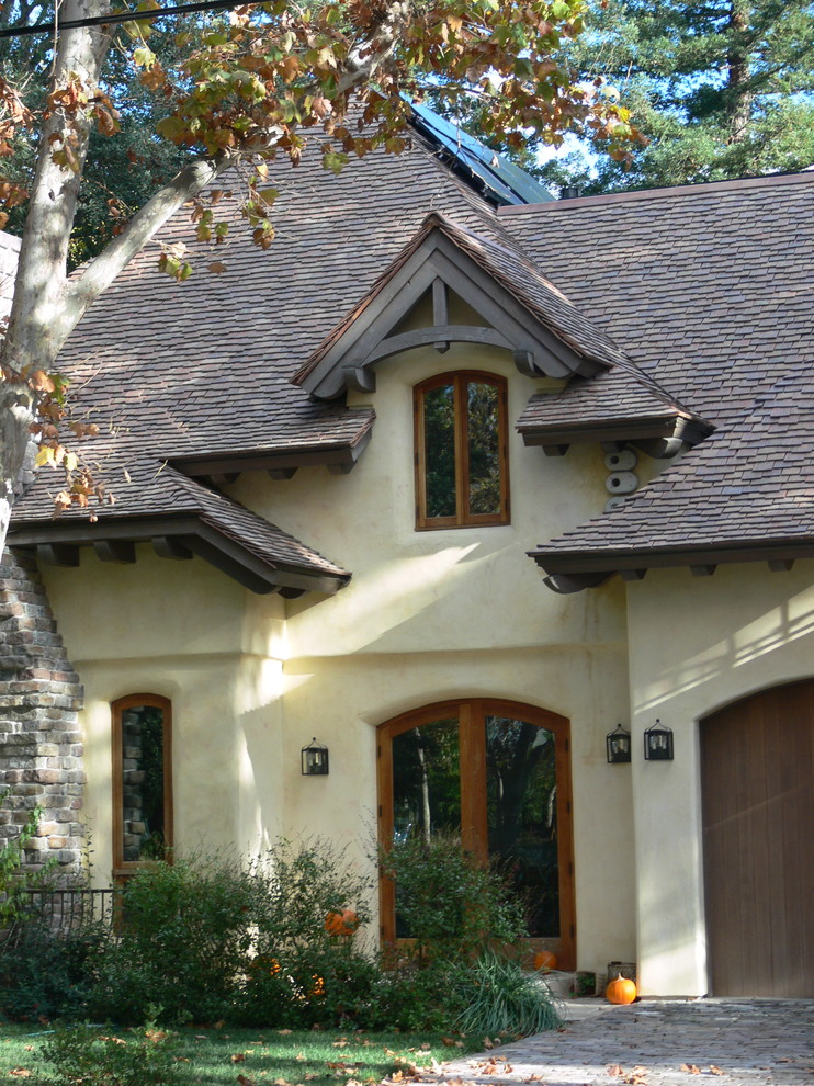 Idee per la facciata di una casa grande beige country a due piani con rivestimento in adobe, tetto a capanna e copertura a scandole