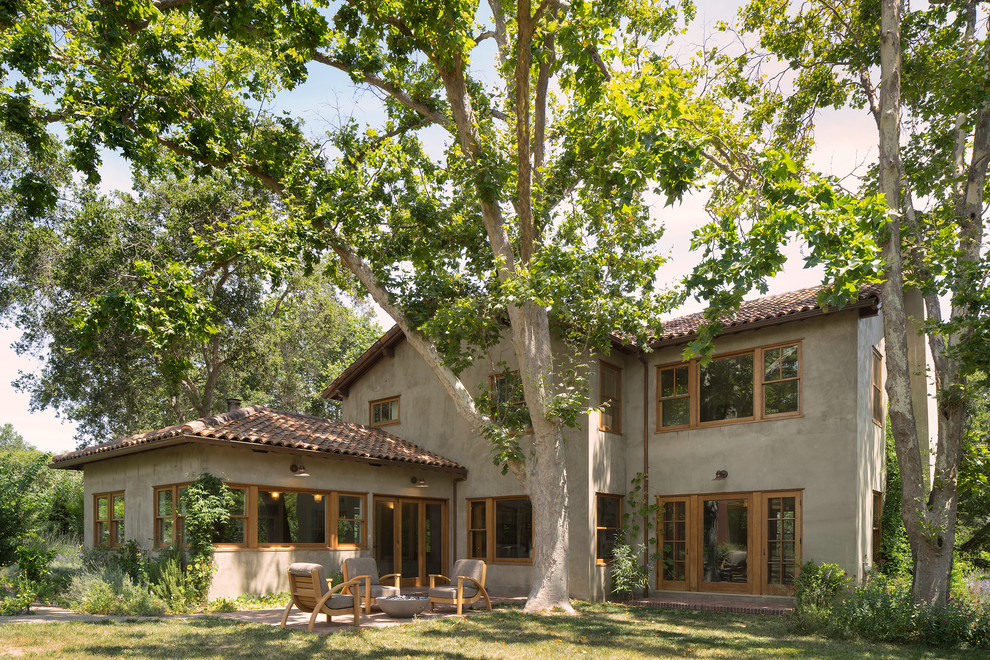Пример оригинального дизайна: большой, двухэтажный, коричневый частный загородный дом в средиземноморском стиле с облицовкой из цементной штукатурки, двускатной крышей и черепичной крышей