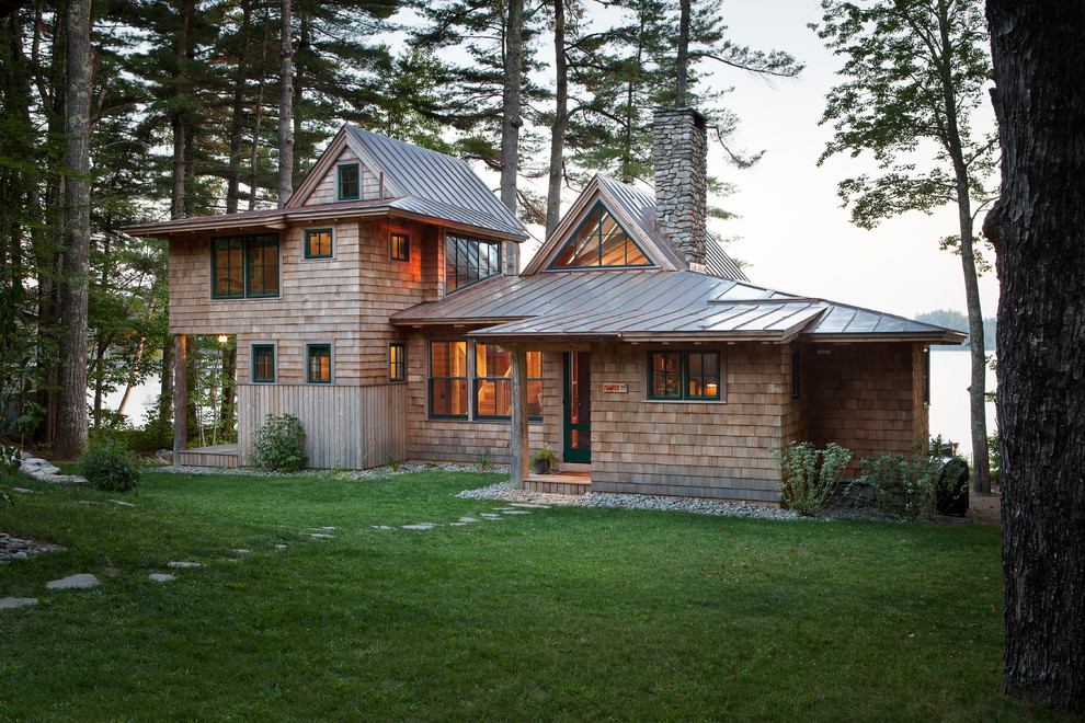 Esempio della villa beige rustica a due piani di medie dimensioni con rivestimento in legno, tetto a capanna e copertura in metallo o lamiera