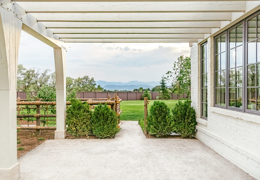 This is an example of a large traditional back patio in Salt Lake City with fencing, gravel and a pergola.