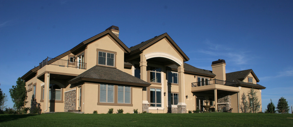 Cette image montre une façade de maison beige traditionnelle en stuc de taille moyenne et à un étage avec un toit à quatre pans et un toit en shingle.