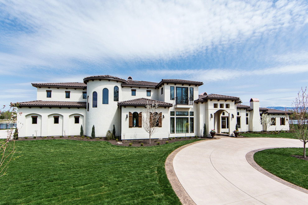 Example of a large tuscan white two-story stucco house exterior design in Boise with a hip roof and a tile roof