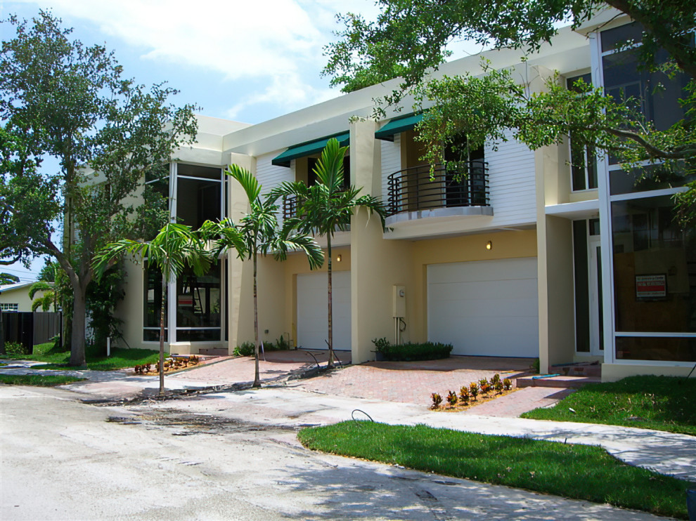 Große, Zweistöckige Moderne Doppelhaushälfte mit Putzfassade, gelber Fassadenfarbe, Flachdach, Misch-Dachdeckung und weißem Dach in Miami