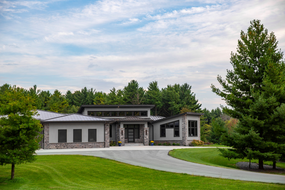 Huge trendy gray two-story stucco house exterior photo in Milwaukee with a metal roof