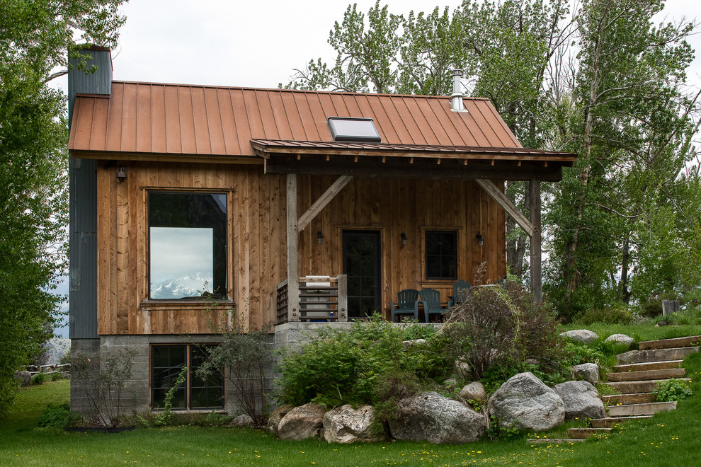 Idée de décoration pour une façade de maison marron chalet en bois de taille moyenne et à un étage avec un toit à quatre pans et un toit en métal.