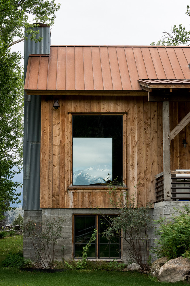 Ejemplo de fachada de casa marrón rústica de tamaño medio de dos plantas con revestimiento de madera, tejado a cuatro aguas y tejado de metal