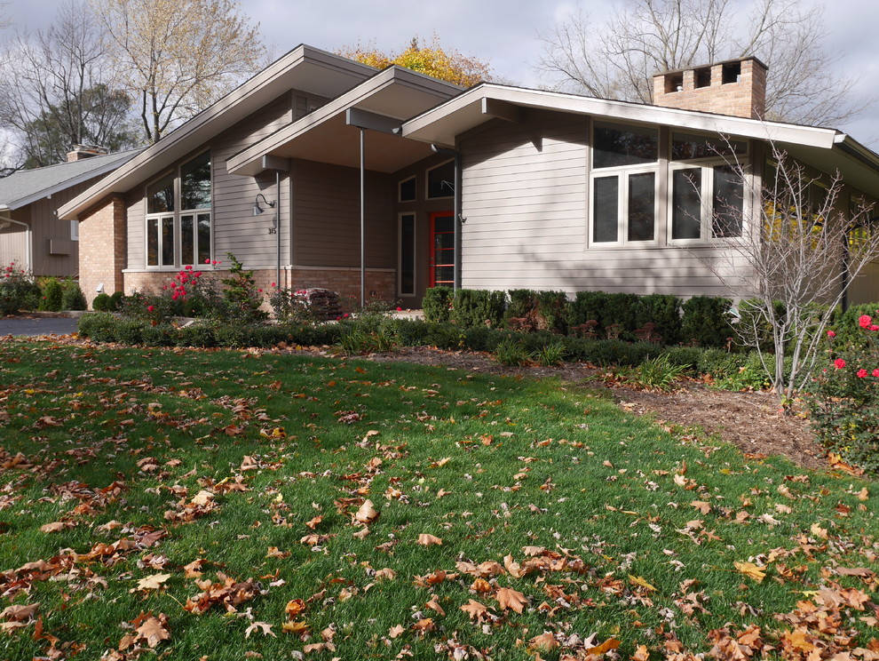 Photo of a beige midcentury bungalow house exterior in Detroit with concrete fibreboard cladding and a lean-to roof.