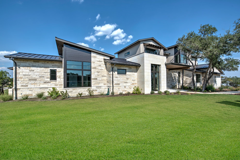 Photo of a large and beige modern two floor house exterior in Austin with stone cladding.