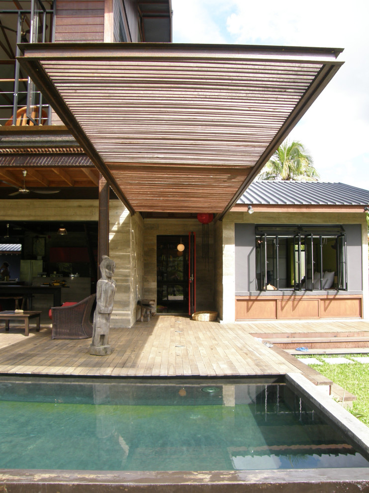 Esempio della villa grigia tropicale a due piani di medie dimensioni con rivestimento in mattoni, tetto a capanna e copertura in metallo o lamiera
