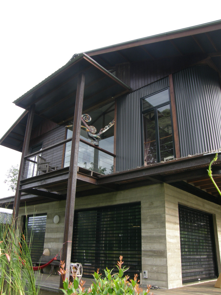 Foto de fachada de casa gris exótica de tamaño medio de dos plantas con revestimiento de hormigón, tejado a dos aguas y tejado de metal