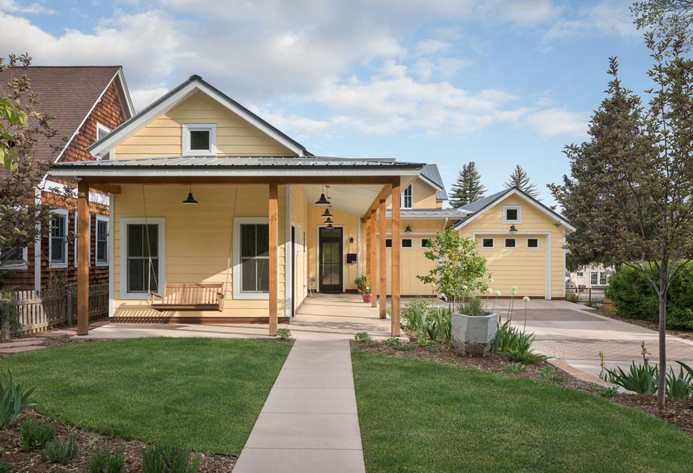 Идея дизайна: одноэтажный, желтый частный загородный дом в стиле кантри с двускатной крышей и металлической крышей