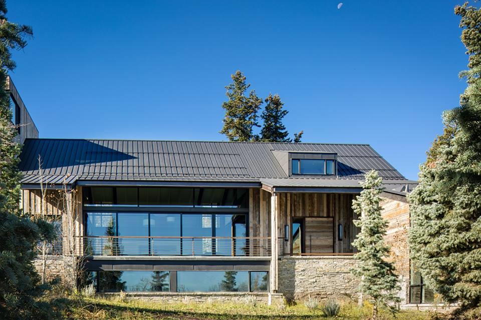Cette photo montre une façade de maison marron montagne en bois de taille moyenne et de plain-pied avec un toit à deux pans et un toit en métal.