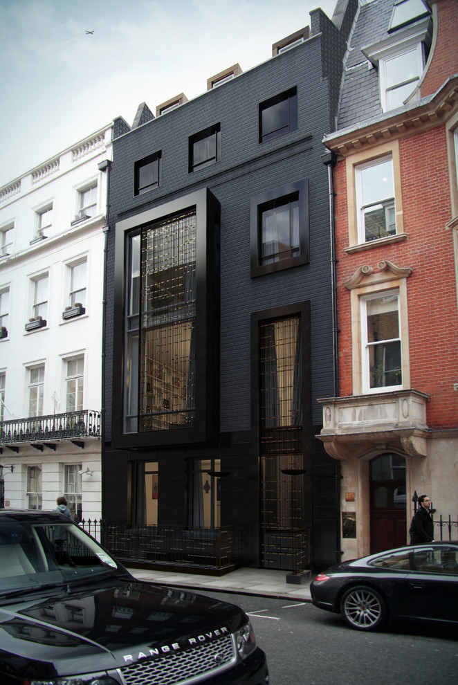 Inspiration för ett funkis svart hus, med tegel och platt tak