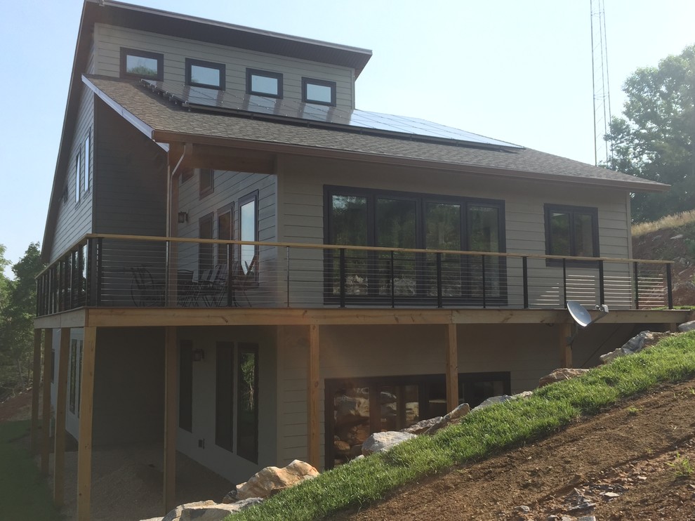 Diseño de fachada de casa beige moderna de tamaño medio de tres plantas con revestimiento de aglomerado de cemento, tejado a cuatro aguas y tejado de teja de madera