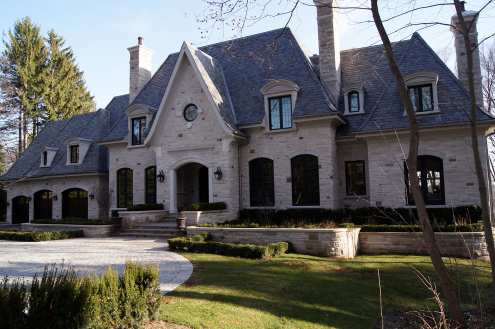 Imagen de fachada beige clásica grande de dos plantas con revestimiento de ladrillo y tejado a cuatro aguas