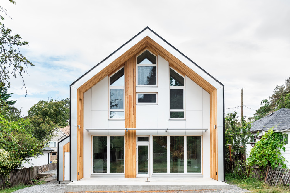 Пример оригинального дизайна: маленький, двухэтажный, белый частный загородный дом в скандинавском стиле с облицовкой из металла, двускатной крышей и металлической крышей для на участке и в саду