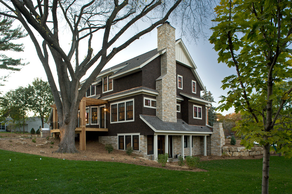 Esempio della facciata di una casa grande marrone classica a tre piani con rivestimento in legno e tetto a capanna