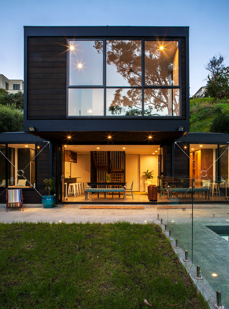 Cette photo montre une façade de maison marron moderne en bois à un étage avec un toit plat.