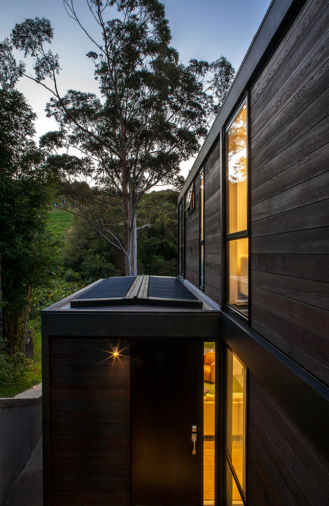 Imagen de fachada marrón moderna de dos plantas con revestimiento de madera y tejado plano