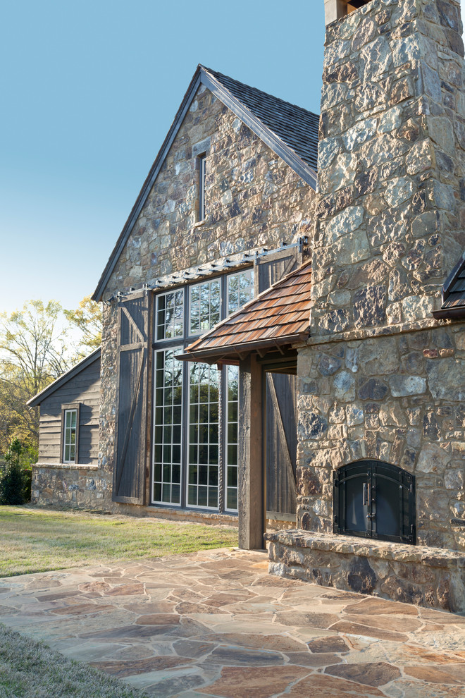 Ejemplo de fachada marrón de estilo de casa de campo grande de tres plantas con revestimiento de piedra y tejado a dos aguas