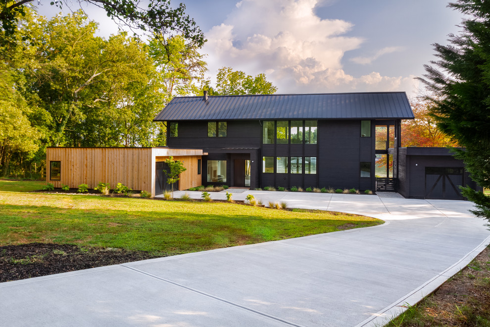 Cette image montre une façade de maison noire design à un étage avec un revêtement mixte, un toit à deux pans et un toit en métal.