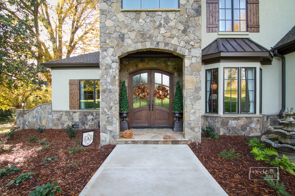 Design ideas for a beige classic house exterior in Charlotte with stone cladding.