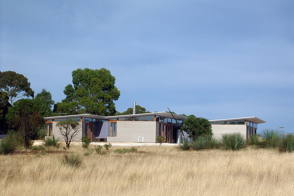 Imagen de fachada blanca actual de una planta con revestimiento de metal y tejado plano