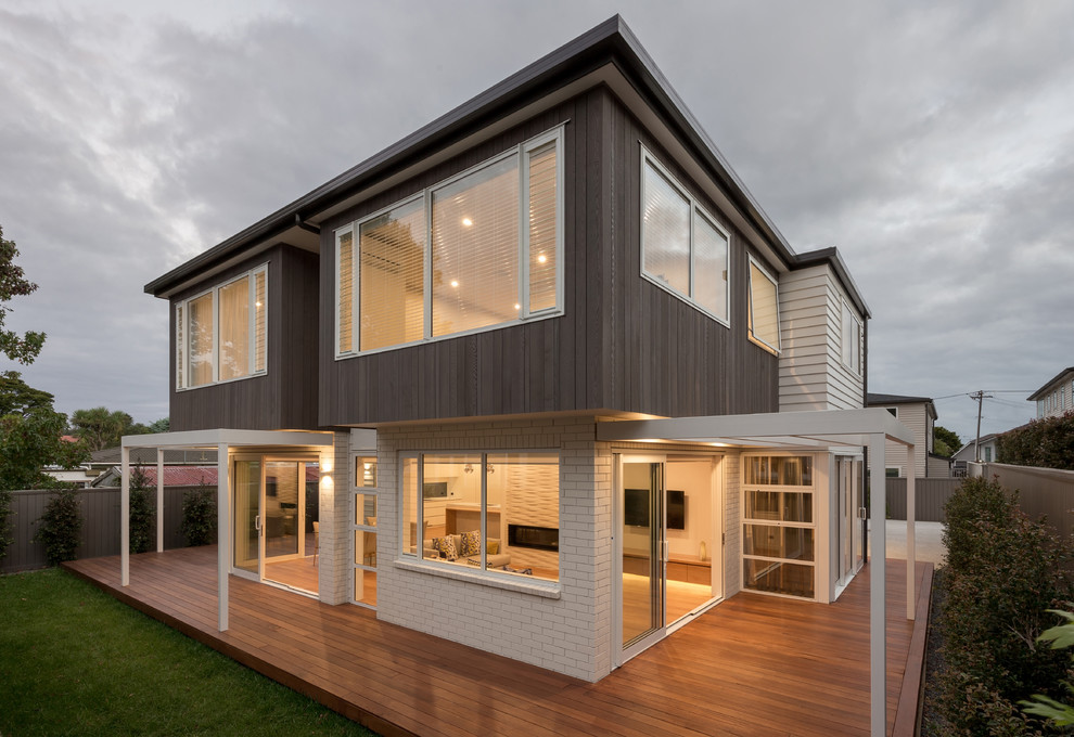 Example of a large trendy white two-story mixed siding exterior home design in Auckland with a hip roof