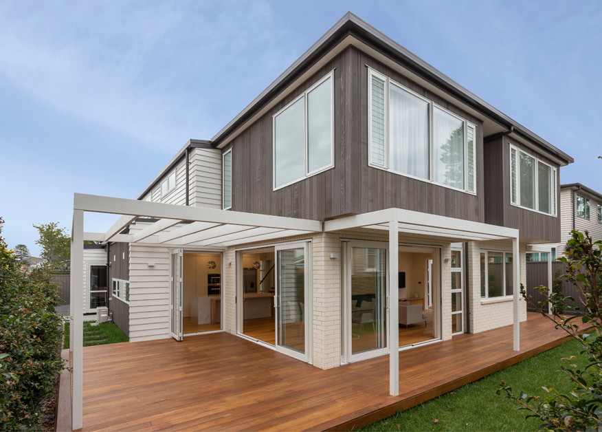 Mid-sized trendy beige two-story mixed siding house exterior photo in Auckland with a hip roof and a metal roof