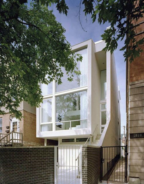 This is an example of a medium sized and white modern terraced house in Chicago with three floors and a flat roof.