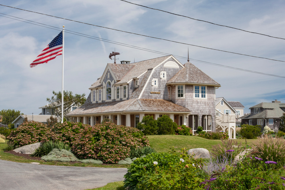 Modelo de fachada de casa beige costera grande de dos plantas con revestimiento de madera, tejado a doble faldón y tejado de teja de madera