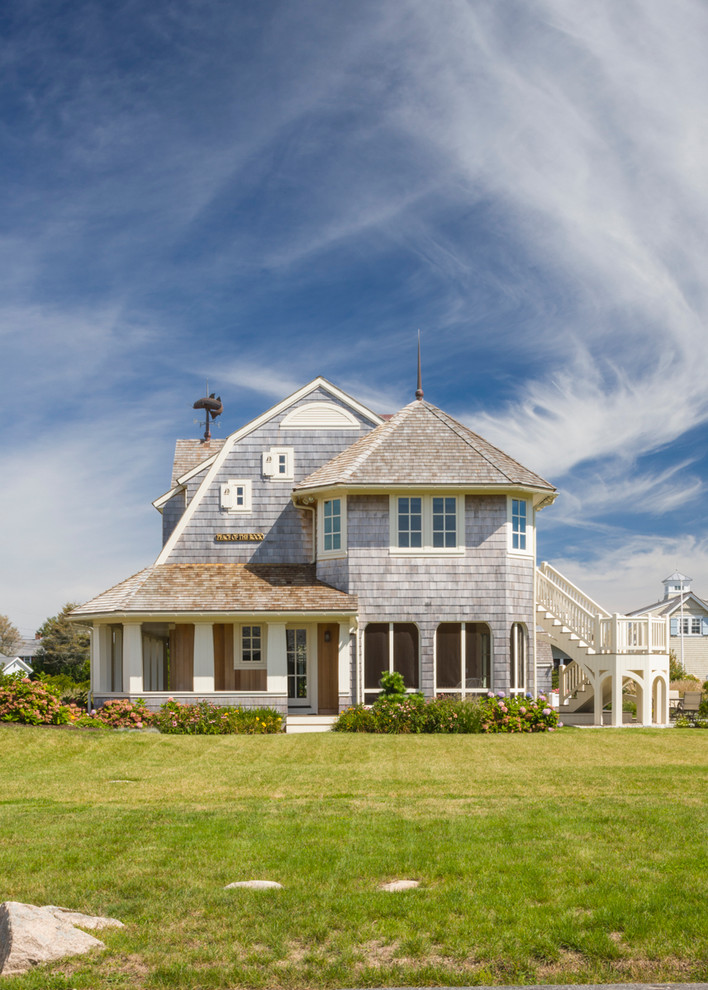 Large ornate beige three-story wood house exterior photo in Boston with a gambrel roof and a shingle roof
