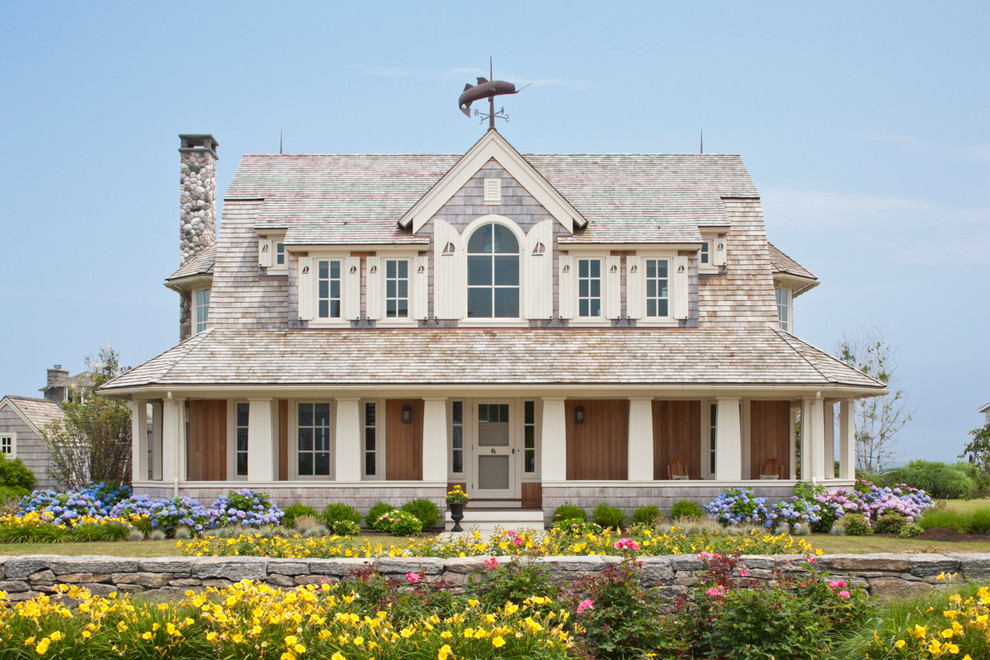 Cette photo montre une grande façade de maison beige bord de mer en bois à un étage avec un toit en shingle.