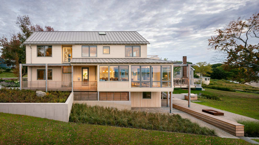 Imagen de fachada de casa beige marinera de dos plantas con revestimiento de madera, tejado a dos aguas y tejado de metal