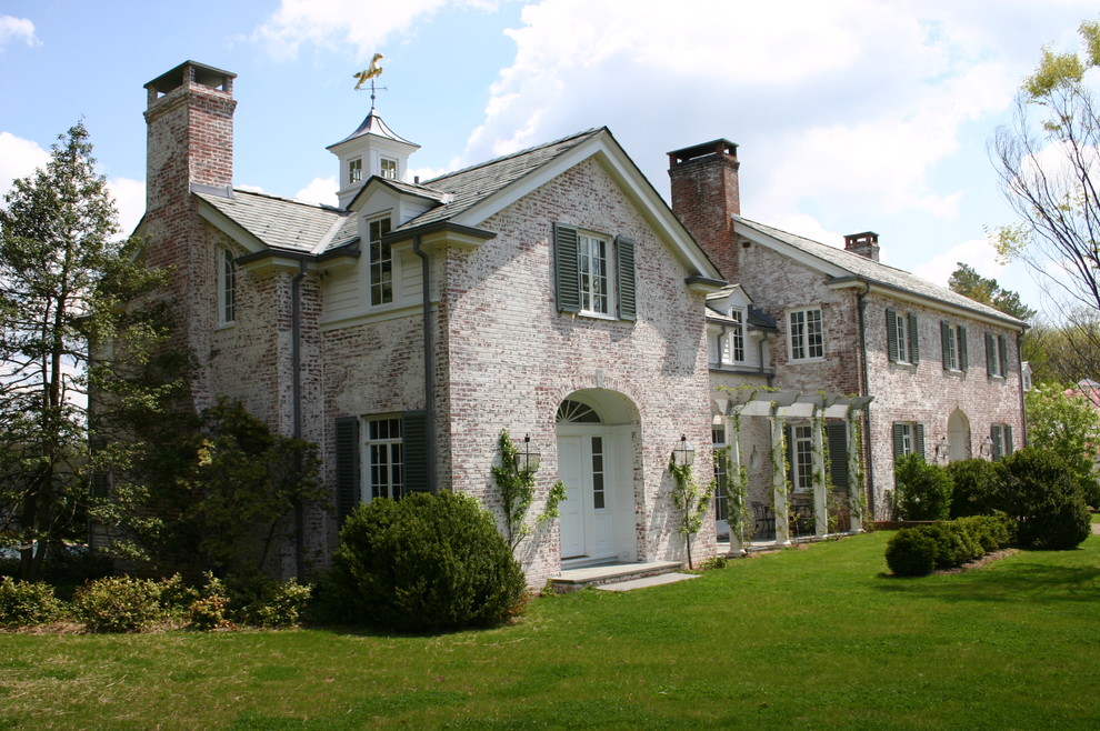 Immagine della facciata di una casa classica a due piani con rivestimento in mattoni