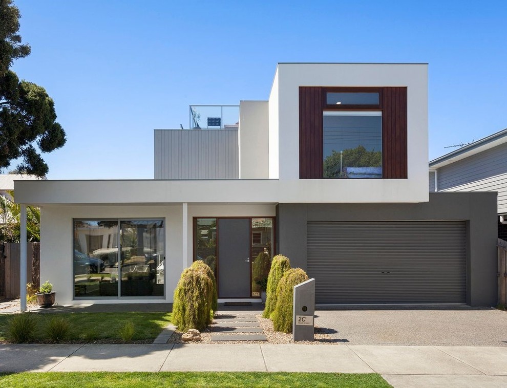 Cette image montre une façade de maison multicolore design de taille moyenne et à un étage avec un revêtement mixte, un toit plat et un toit en métal.