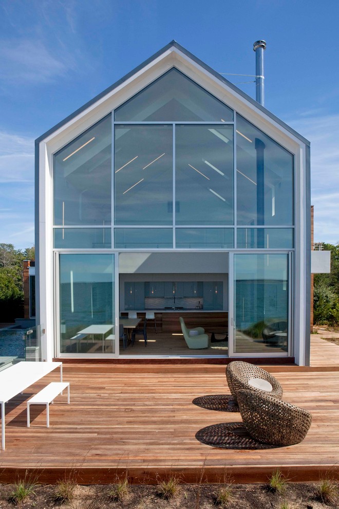 Immagine della facciata di una casa contemporanea a due piani con rivestimento in vetro e tetto a capanna