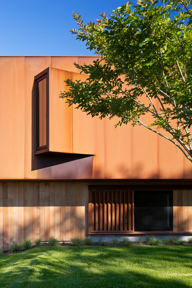 Imagen de fachada de casa minimalista con revestimiento de metal, tejado plano y techo verde