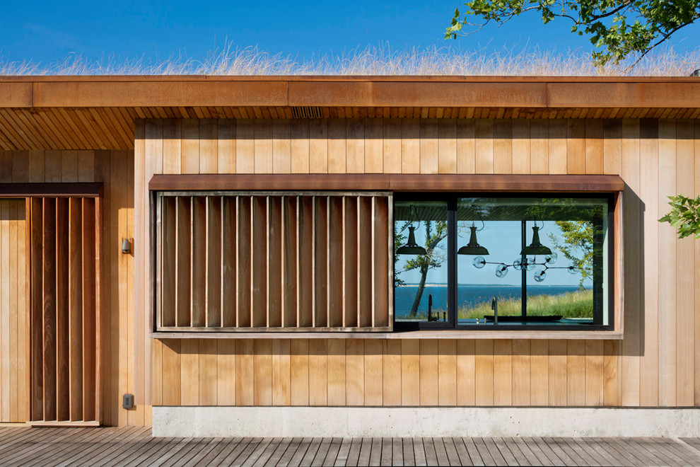 Foto de fachada de casa minimalista con revestimiento de madera, tejado plano y techo verde