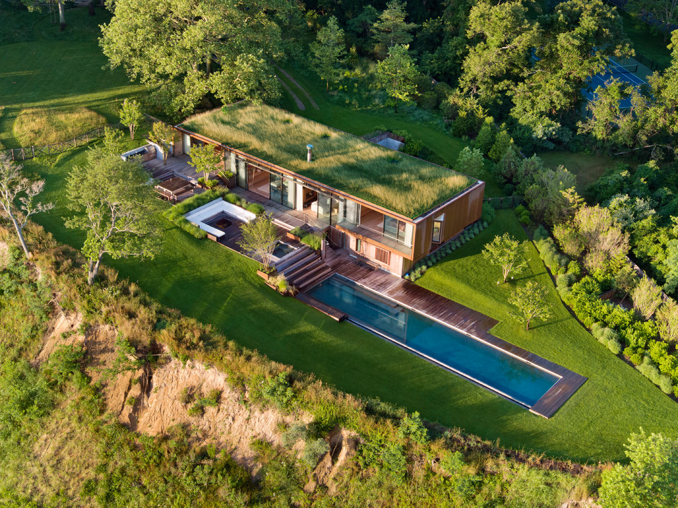 Идея дизайна: деревянный частный загородный дом в стиле модернизм с плоской крышей и зеленой крышей