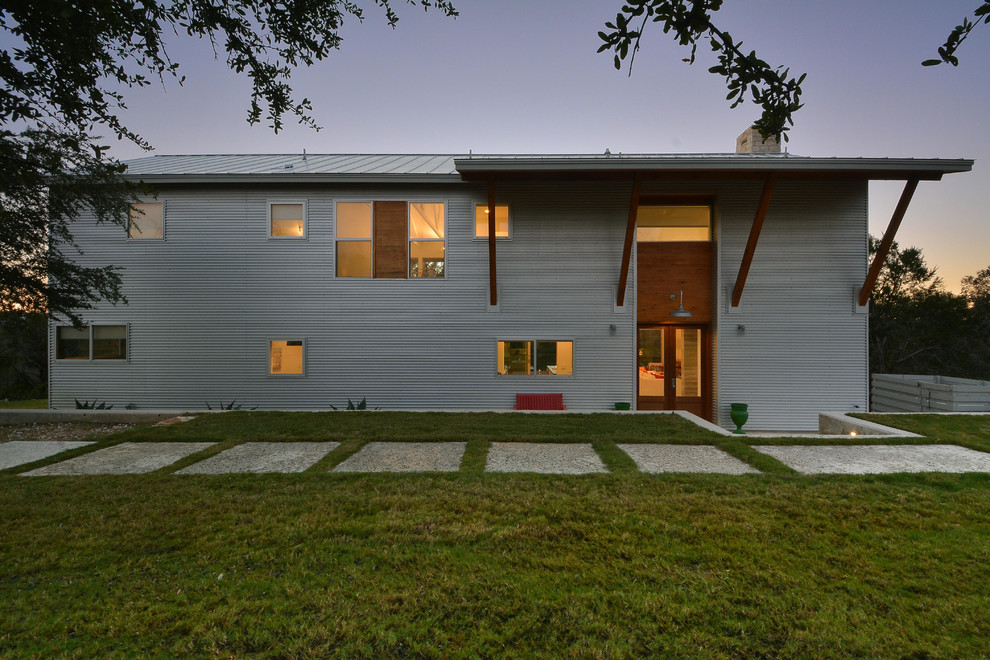 Inspiration for a large and gey industrial two floor house exterior in Austin with metal cladding and a flat roof.