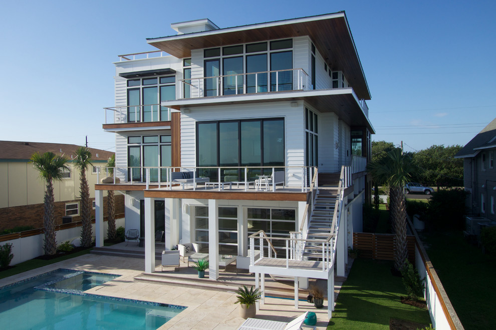 Cette image montre une grande façade de maison grise minimaliste en bois à deux étages et plus avec un toit plat.