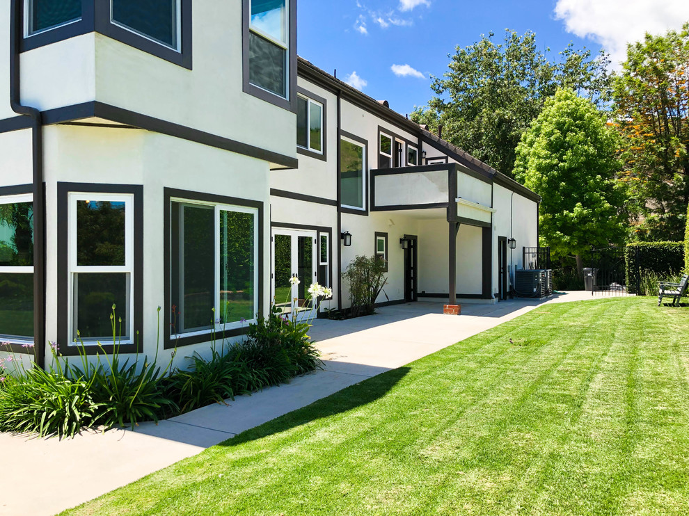 Mittelgroßes, Zweistöckiges Modernes Einfamilienhaus mit Putzfassade, beiger Fassadenfarbe, Schindeldach, braunem Dach, Walmdach und Wandpaneelen in Los Angeles